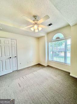 121 Pinnacle Ln, Mcdonough, GA 30253 - unfurnished bedroom with a textured ceiling, carpet flooring, and ceiling fan