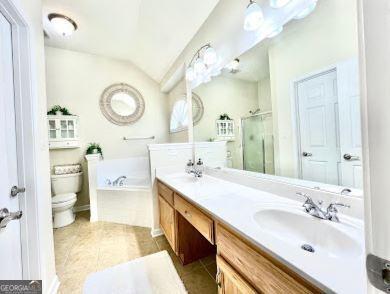 121 Pinnacle Ln, Mcdonough, GA 30253 - bathroom featuring a stall shower, double vanity, a garden tub, vaulted ceiling, and tile patterned flooring