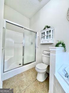 121 Pinnacle Ln, Mcdonough, GA 30253 - bathroom featuring an enclosed shower, tile patterned flooring, a bath, and a textured ceiling