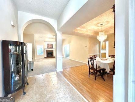 121 Pinnacle Ln, Mcdonough, GA 30253 - tiled dining area featuring arched walkways, a fireplace with raised hearth, a chandelier, and a textured ceiling