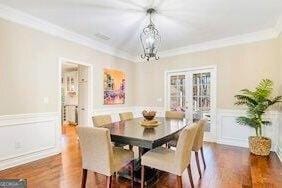 380 Victorian Ln, Duluth, GA 30097 - dining space featuring crown molding, wood finished floors, wainscoting, a chandelier, and a decorative wall