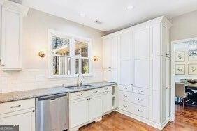 380 Victorian Ln, Duluth, GA 30097 - kitchen with stainless steel dishwasher, white cabinetry, wood finished floors, backsplash, and light stone countertops