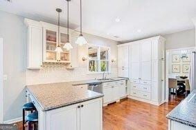 380 Victorian Ln, Duluth, GA 30097 - kitchen featuring white cabinetry, glass insert cabinets, wood finished floors, and hanging light fixtures