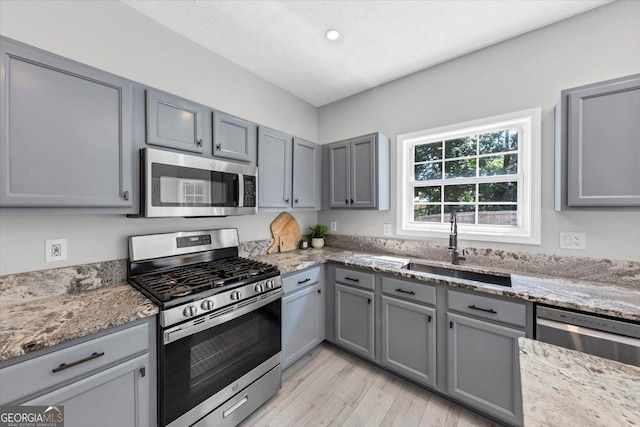 5195 Oaks Landing Ct, Sugar Hill, GA 30518 - kitchen featuring appliances with stainless steel finishes, gray cabinets, light wood-style floors, light stone countertops, and recessed lighting