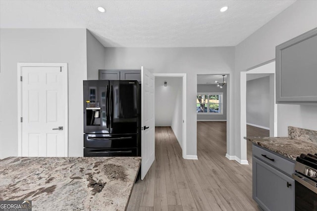 5195 Oaks Landing Ct, Sugar Hill, GA 30518 - kitchen with gray cabinetry, black refrigerator with ice dispenser, light wood-style flooring, light stone countertops, and ceiling fan
