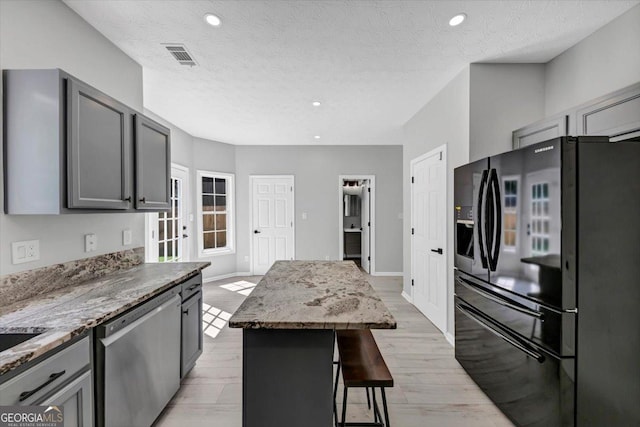 5195 Oaks Landing Ct, Sugar Hill, GA 30518 - kitchen featuring black refrigerator with ice dispenser, stainless steel dishwasher, gray cabinetry, light stone countertops, and a textured ceiling