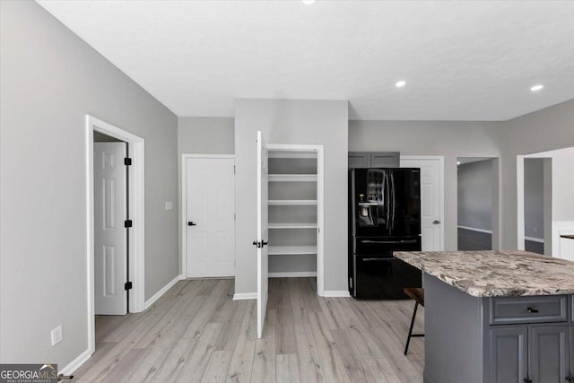 5195 Oaks Landing Ct, Sugar Hill, GA 30518 - kitchen with black fridge with ice dispenser, gray cabinets, light wood finished floors, light stone counters, and recessed lighting