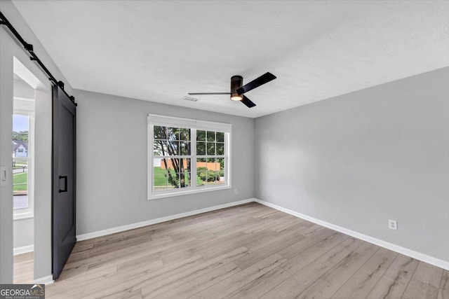 5195 Oaks Landing Ct, Sugar Hill, GA 30518 - spare room featuring light wood-style floors, a barn door, and ceiling fan
