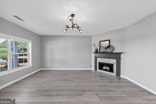 5195 Oaks Landing Ct, Sugar Hill, GA 30518 - unfurnished living room featuring wood finished floors, a chandelier, a premium fireplace, and a textured ceiling