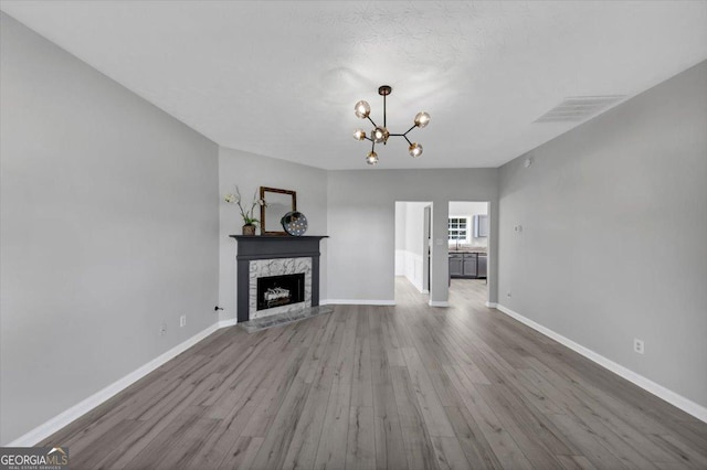 5195 Oaks Landing Ct, Sugar Hill, GA 30518 - unfurnished living room with wood finished floors, a chandelier, and a premium fireplace