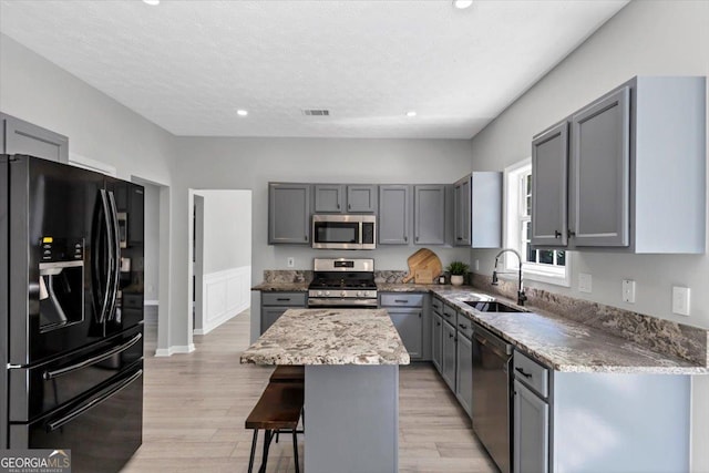 5195 Oaks Landing Ct, Sugar Hill, GA 30518 - kitchen featuring appliances with stainless steel finishes, gray cabinets, a kitchen bar, light stone countertops, and recessed lighting