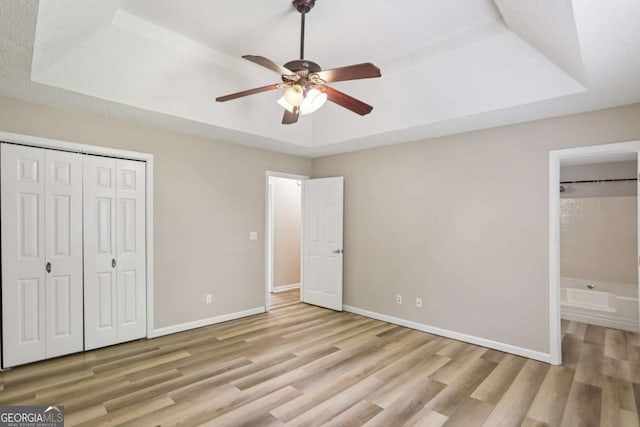 73 Azalea Dr, Villa Rica, GA 30180 - unfurnished bedroom with a tray ceiling, wood finished floors, ensuite bath, a closet, and a ceiling fan