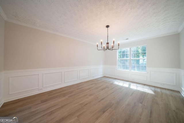 4815 Price St, Forest Park, GA 30297 - empty room featuring a chandelier, a textured ceiling, wood finished floors, wainscoting, and a decorative wall