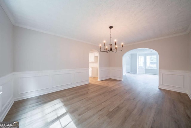 4815 Price St, Forest Park, GA 30297 - unfurnished dining area with arched walkways, a chandelier, wood finished floors, wainscoting, and a decorative wall