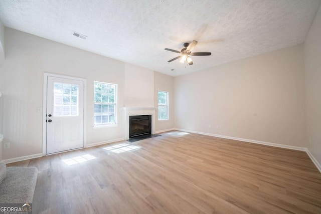 4815 Price St, Forest Park, GA 30297 - unfurnished living room with light wood finished floors, a ceiling fan, a textured ceiling, and a glass covered fireplace