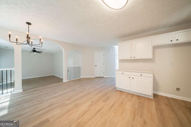 4815 Price St, Forest Park, GA 30297 - unfurnished living room with a ceiling fan, a chandelier, light wood finished floors, a textured ceiling, and arched walkways