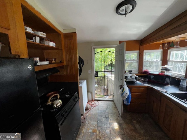 6733 Old Covington Rd, Lithonia, GA 30058 - kitchen featuring range with gas stovetop, brown cabinets, stone finish floors, open shelves, and freestanding refrigerator
