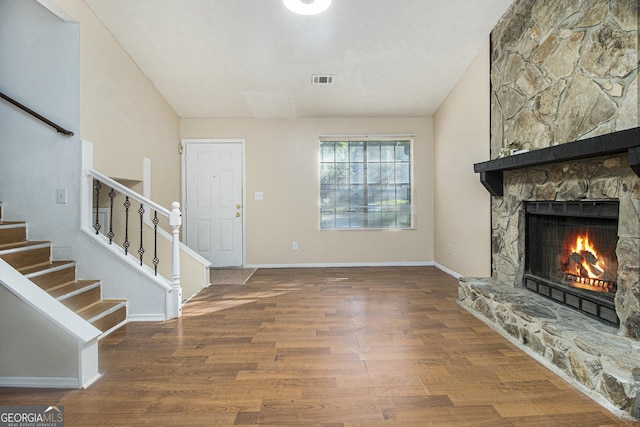 1077 Mainstreet Valley Dr, Stone Mountain, GA 30088 - unfurnished living room with stairway, a fireplace, and wood finished floors