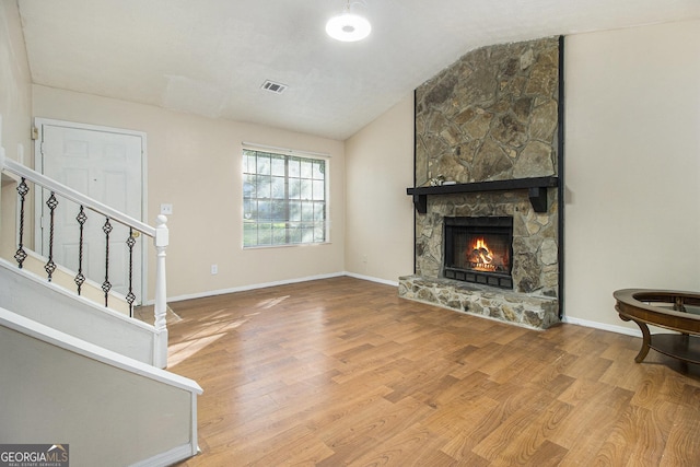 1077 Mainstreet Valley Dr, Stone Mountain, GA 30088 - unfurnished living room featuring vaulted ceiling, wood finished floors, stairway, and a fireplace