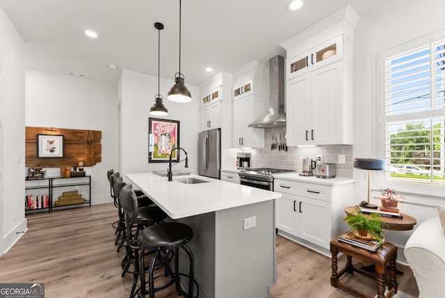 306 Clarendon Ct SE, Gainesville, GA 30501 - kitchen featuring wall chimney exhaust hood, appliances with stainless steel finishes, tasteful backsplash, light wood finished floors, and a kitchen bar
