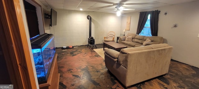 1605 Cody Rd, Mount Airy, GA 30563 - living room with a drop ceiling, a wood stove, a ceiling fan, concrete flooring, and concrete block wall