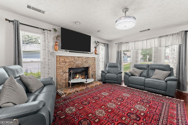 625 Hickory Nobb, Sugar Hill, GA 30518 - living room featuring a textured ceiling, a stone fireplace, and wood finished floors
