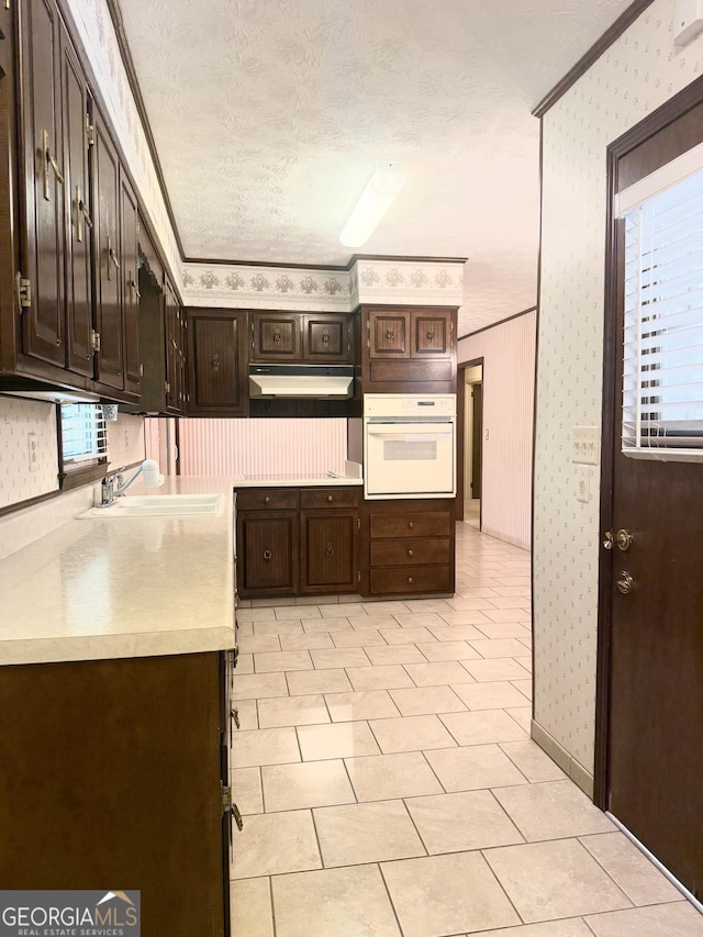 10 Montre Cir SE, Silver Creek, GA 30173 - kitchen with white oven, wallpapered walls, under cabinet range hood, light countertops, and crown molding