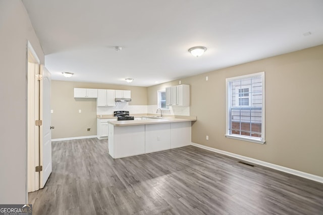 1159 Smith St SW, Atlanta, GA 30310 - kitchen with black stove, a peninsula, wood finished floors, light countertops, and white cabinets