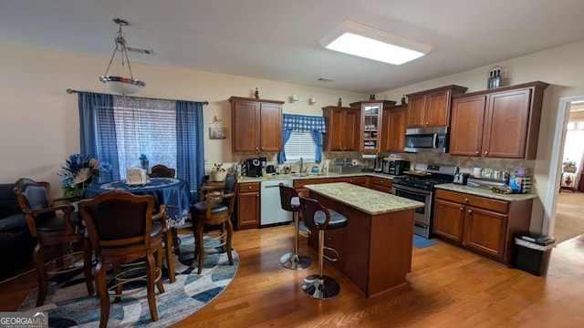 2435 Hickory Station Cir, Snellville, GA 30078 - kitchen featuring stainless steel appliances, light wood-style flooring, decorative backsplash, and a kitchen island