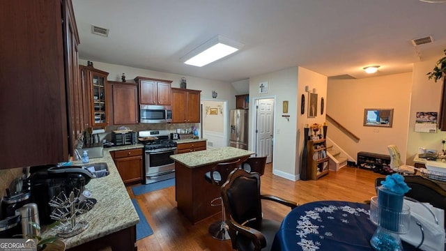 2435 Hickory Station Cir, Snellville, GA 30078 - kitchen featuring appliances with stainless steel finishes, dark wood-style floors, a kitchen island, glass insert cabinets, and a kitchen bar