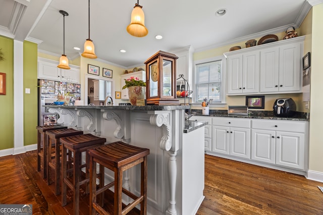 290 Vinson Rd, Tignall, GA 30668 - kitchen with a breakfast bar area, dark wood-type flooring, white cabinets, crown molding, and dark countertops