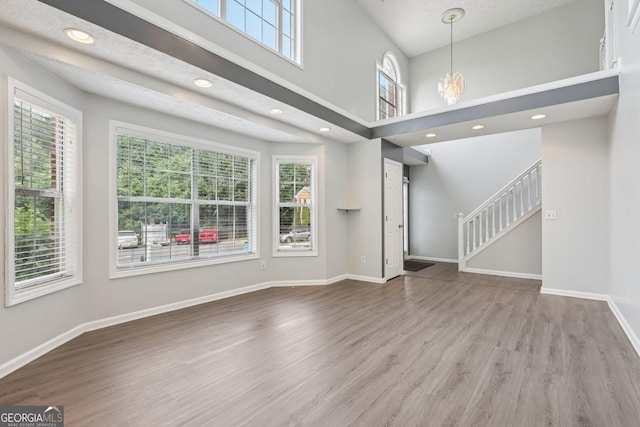 2379 Fallbrook Ct, Duluth, GA 30096 - unfurnished living room with stairway, wood finished floors, a chandelier, recessed lighting, and a towering ceiling