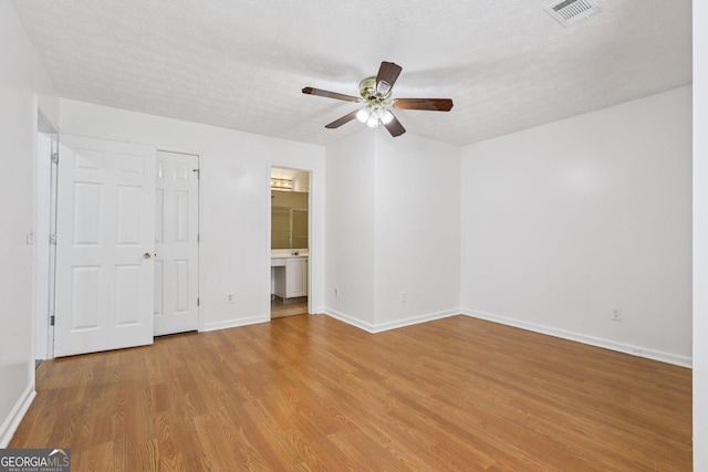 2379 Fallbrook Ct, Duluth, GA 30096 - unfurnished bedroom with wood finished floors, a ceiling fan, a textured ceiling, and connected bathroom