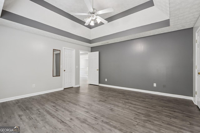 2379 Fallbrook Ct, Duluth, GA 30096 - spare room featuring a tray ceiling, a ceiling fan, and dark wood finished floors