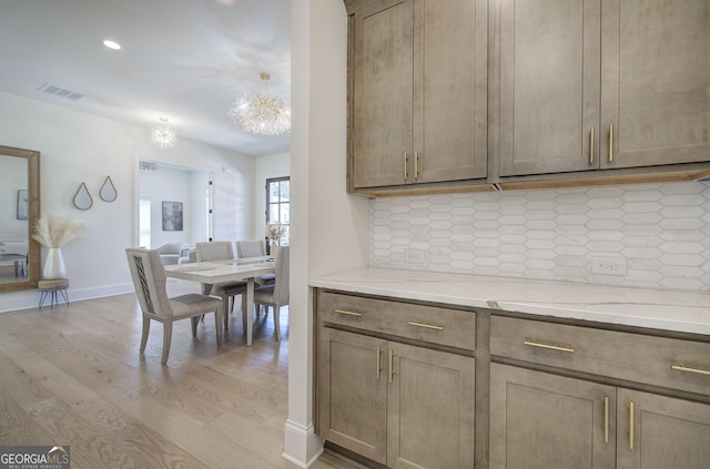 841 Keystone Dr, Woodstock, GA 30188 - kitchen with a chandelier, tasteful backsplash, light wood finished floors, and light stone countertops