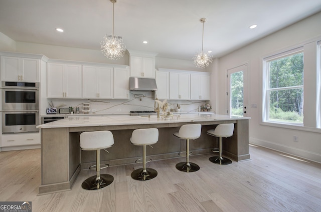 841 Keystone Dr, Woodstock, GA 30188 - kitchen featuring stainless steel double oven, light wood-type flooring, white cabinetry, a large island with sink, and recessed lighting