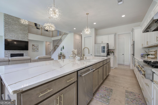 841 Keystone Dr, Woodstock, GA 30188 - kitchen featuring stainless steel appliances, a chandelier, ventilation hood, a fireplace, and open floor plan