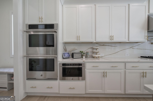 841 Keystone Dr, Woodstock, GA 30188 - kitchen with stainless steel double oven, white cabinetry, and light stone countertops