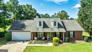 125 Meadow View Dr, Jackson, GA 30233 - cape cod house with concrete driveway, an attached garage, a front yard, and a porch