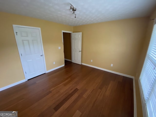 1472 Queenie Smith Rd NE, Conyers, GA 30012 - unfurnished bedroom featuring dark wood-style flooring and rail lighting