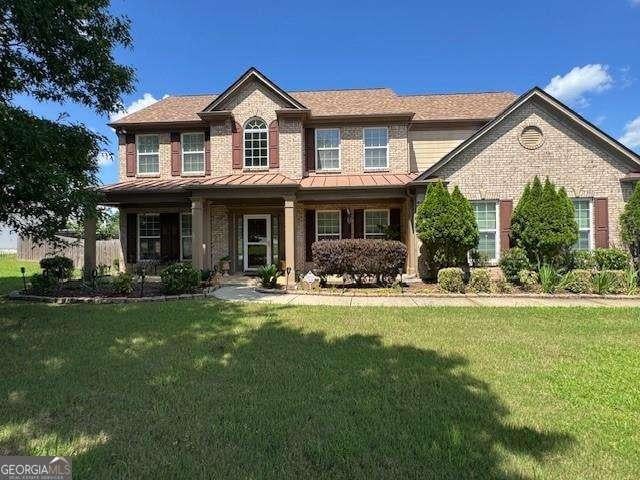 7880 Cavendish Pl, Suwanee, GA 30024 - view of front of property featuring a standing seam roof, a front yard, brick siding, a shingled roof, and a metal roof