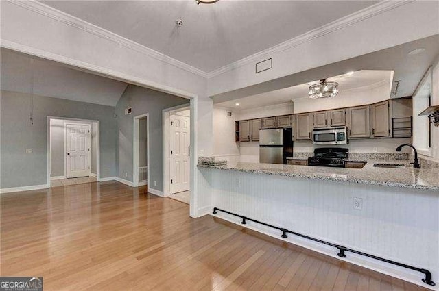 1010 Donegal SE, Smyrna, GA 30080 - kitchen with stainless steel appliances, wood finished floors, light stone counters, crown molding, and a peninsula