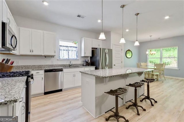 286 Kimberleys Xing, Jasper, GA 30143 - kitchen with stainless steel appliances, a kitchen breakfast bar, light wood-style flooring, a center island, and white cabinetry