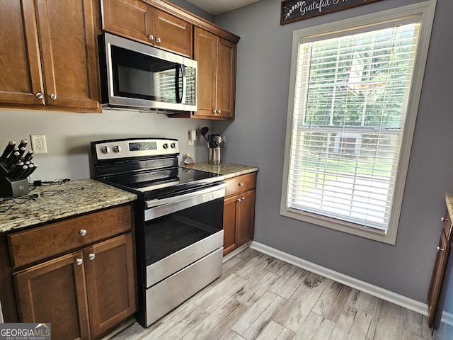 100 Lexington Pl, Senoia, GA 30276 - kitchen featuring stainless steel appliances, plenty of natural light, light wood-style flooring, and light stone counters