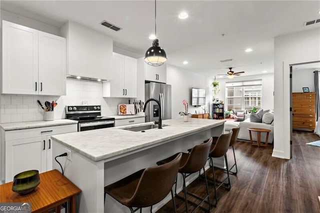 12 Becker Pl NW, Atlanta, GA 30307 - kitchen with stainless steel appliances, a ceiling fan, decorative backsplash, dark wood finished floors, and a kitchen bar