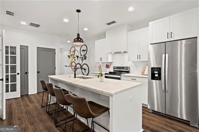 12 Becker Pl NW, Atlanta, GA 30307 - kitchen with appliances with stainless steel finishes, a center island with sink, white cabinetry, hanging light fixtures, and a kitchen breakfast bar