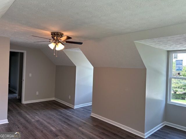 433 Rhett Dr, Loganville, GA 30052 - additional living space with a textured ceiling, vaulted ceiling, dark wood-style flooring, and ceiling fan