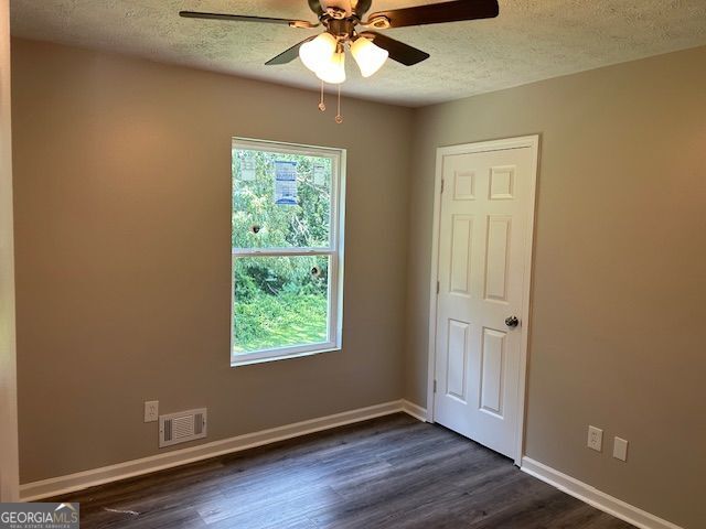 433 Rhett Dr, Loganville, GA 30052 - spare room featuring a textured ceiling, ceiling fan, and dark wood-style floors