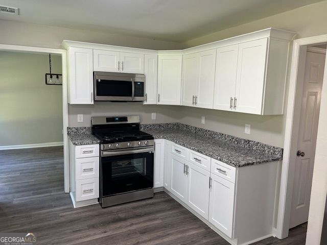 433 Rhett Dr, Loganville, GA 30052 - kitchen featuring stainless steel appliances, white cabinetry, dark wood-style flooring, and dark stone countertops