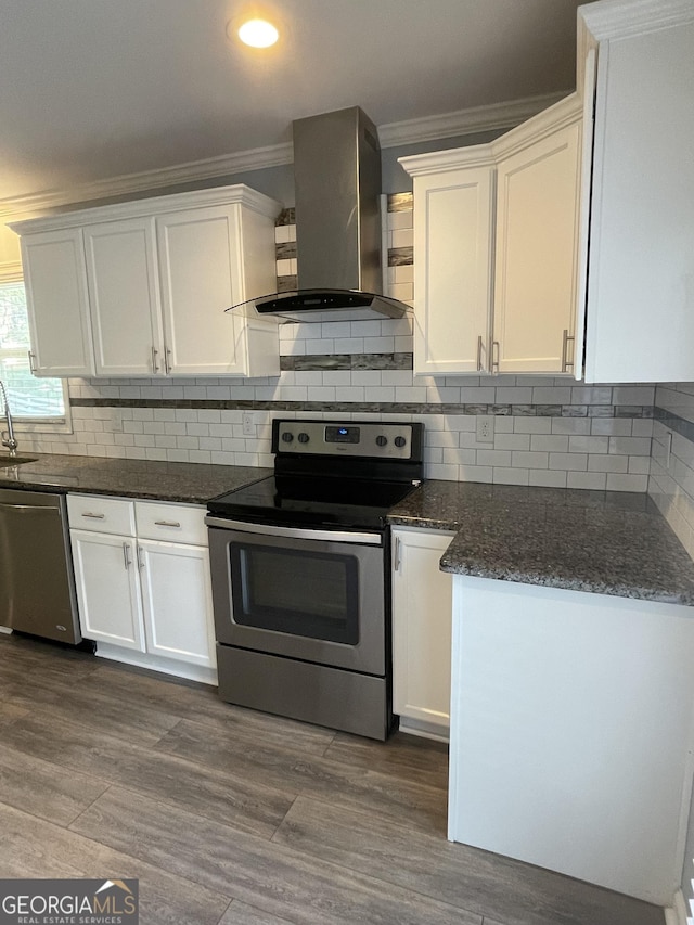 1833 Phillips Ave, East Point, GA 30344 - kitchen featuring appliances with stainless steel finishes, wall chimney exhaust hood, ornamental molding, white cabinets, and dark wood finished floors